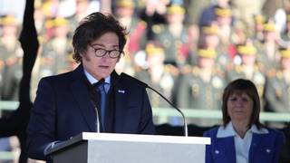 Presidente Javier Milei durante un acto oficial, con la bandera argentina de fondo.