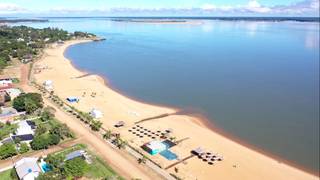 Vista del río y la costanera de Paso de la Patria, Corrientes, con pescadores y familias disfrutando de la naturaleza.