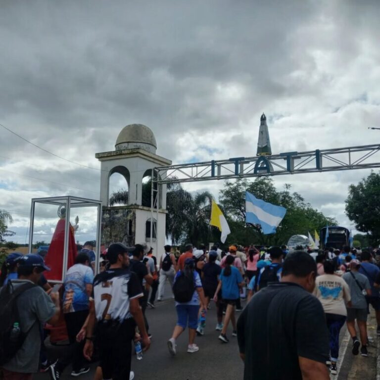 Grupo de peregrinos caminando por la ruta hacia la Basílica de Itatí, bajo un cielo nublado.
