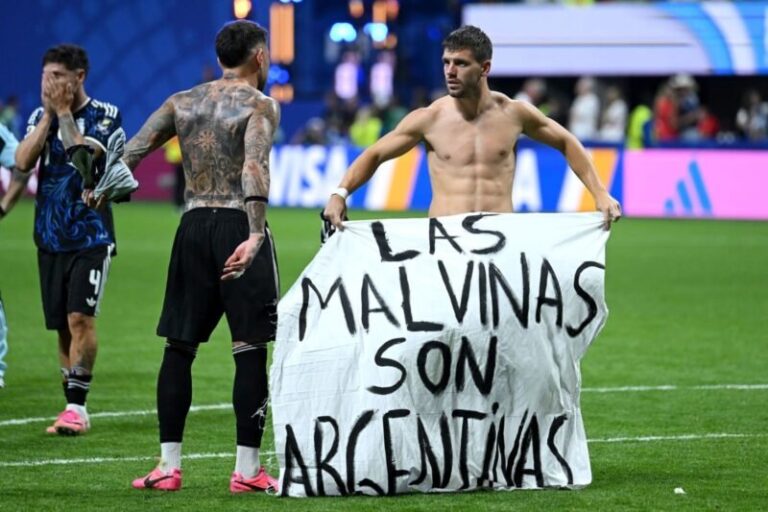 Jugadores de la Selección argentina sosteniendo una bandera blanca con la leyenda Las Malvinas son argentinas en el césped del Mercedes-Benz Stadium
