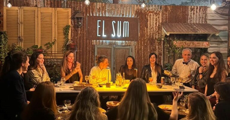 Personas compartiendo una cena en una mesa larga, en un evento de cenas para solteros